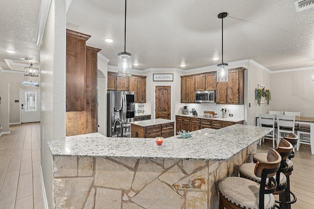 kitchen featuring visible vents, light wood-style flooring, stainless steel appliances, a textured ceiling, and crown molding