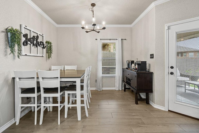 dining space with ornamental molding, a notable chandelier, baseboards, and wood finished floors