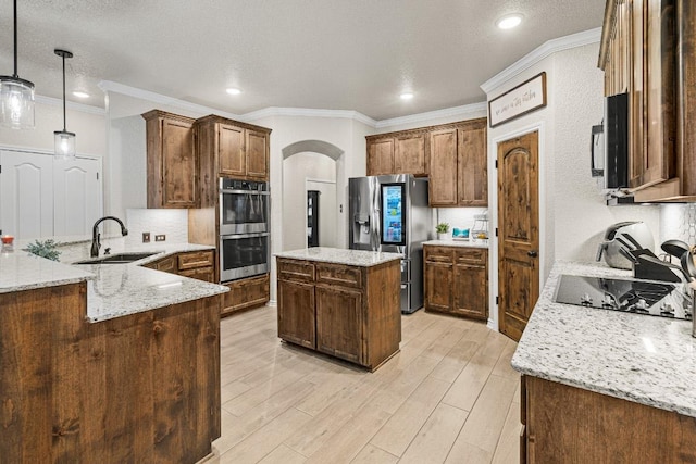 kitchen featuring arched walkways, stainless steel appliances, a sink, light wood-style floors, and a center island