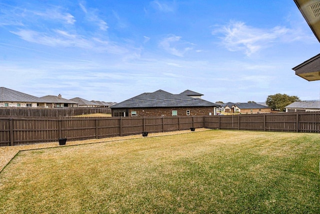 view of yard featuring a fenced backyard and a residential view