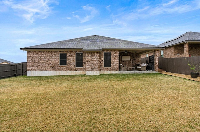 rear view of house with a patio area, a fenced backyard, a yard, and brick siding