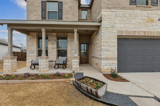 view of exterior entry with a garage, covered porch, brick siding, and stone siding