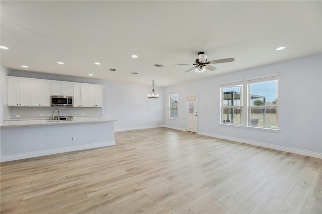 interior space with light countertops, stainless steel microwave, visible vents, decorative backsplash, and open floor plan