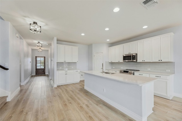 kitchen with light wood finished floors, visible vents, stainless steel appliances, light countertops, and a sink