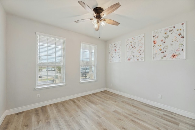 spare room featuring light wood-type flooring, a ceiling fan, and baseboards