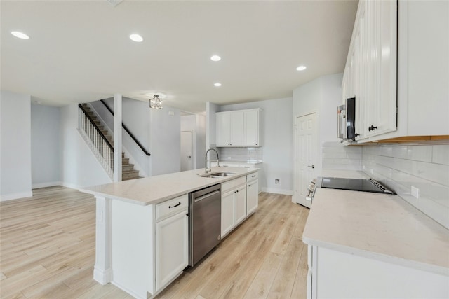 kitchen featuring appliances with stainless steel finishes, backsplash, a sink, and light wood-style floors