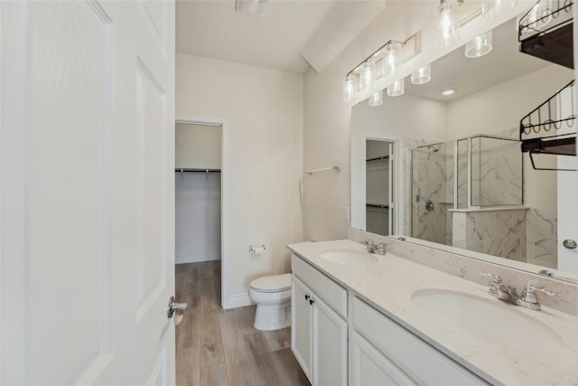 full bathroom with toilet, a tile shower, a sink, and wood finished floors