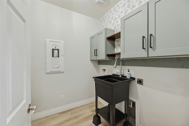 clothes washing area featuring hookup for a washing machine, hookup for an electric dryer, baseboards, cabinet space, and light wood finished floors