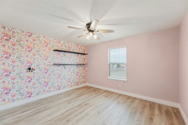 unfurnished room featuring wallpapered walls, light wood-type flooring, a ceiling fan, and baseboards