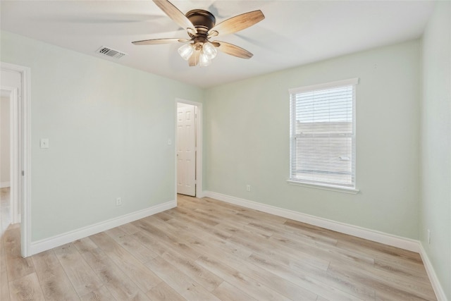 spare room featuring a ceiling fan, light wood-type flooring, visible vents, and baseboards