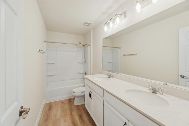 bathroom with toilet, wood finished floors, a sink, and visible vents