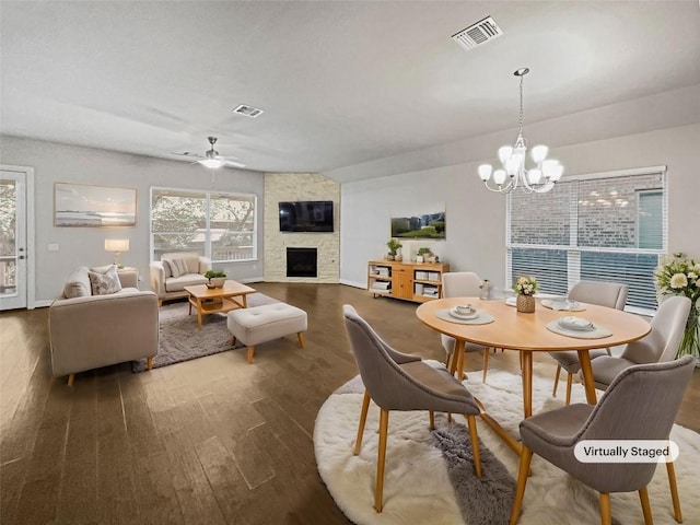 dining space featuring ceiling fan with notable chandelier, visible vents, a fireplace, and wood finished floors