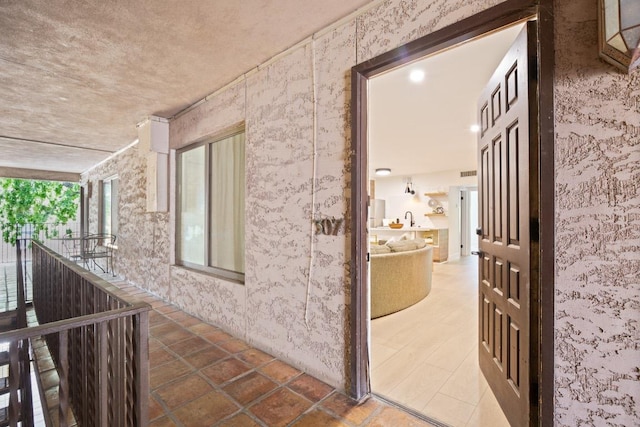 corridor featuring a sink and wallpapered walls