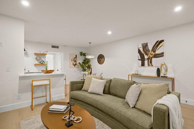 living room with light wood-style flooring, recessed lighting, visible vents, and baseboards