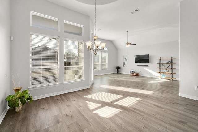 unfurnished living room featuring ceiling fan with notable chandelier, wood finished floors, visible vents, and baseboards