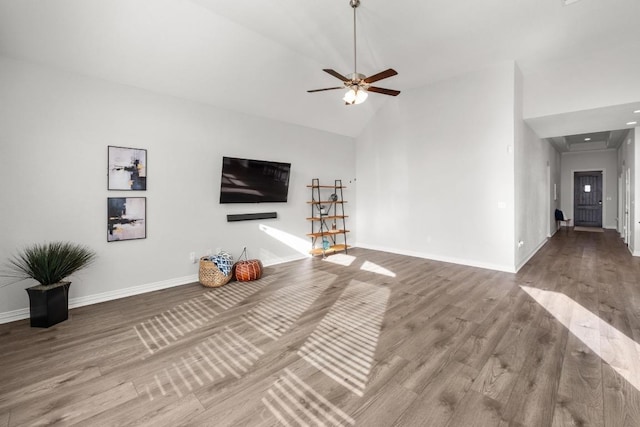 unfurnished living room featuring high vaulted ceiling, ceiling fan, baseboards, and wood finished floors