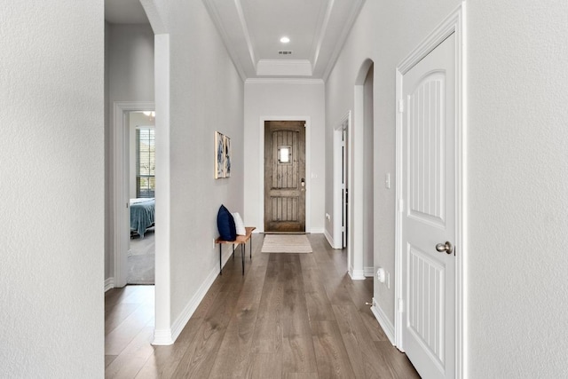 interior space with ornamental molding, arched walkways, baseboards, and wood finished floors