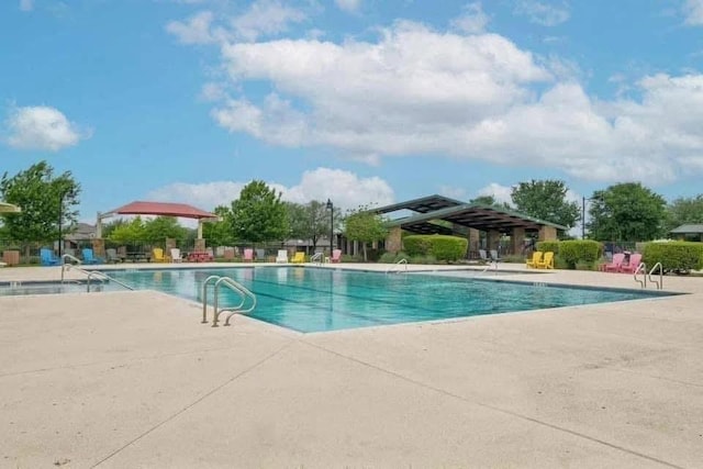 community pool with a patio area and fence