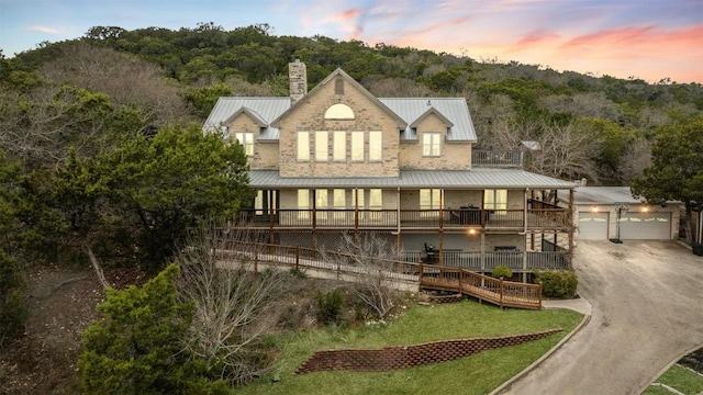 back of house with a garage, a balcony, metal roof, an outbuilding, and a standing seam roof