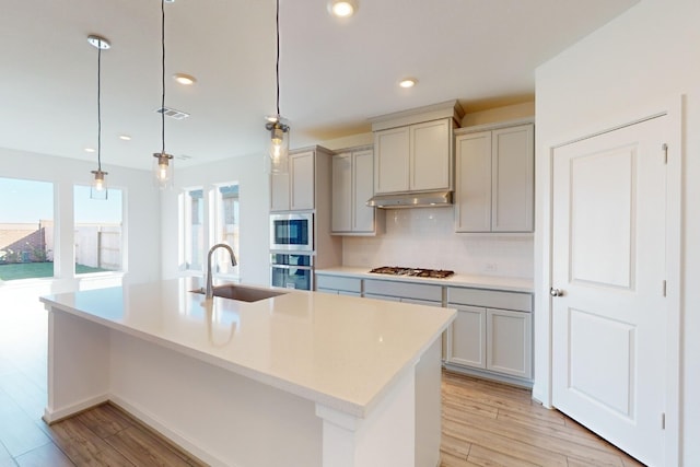 kitchen with under cabinet range hood, a sink, visible vents, appliances with stainless steel finishes, and backsplash