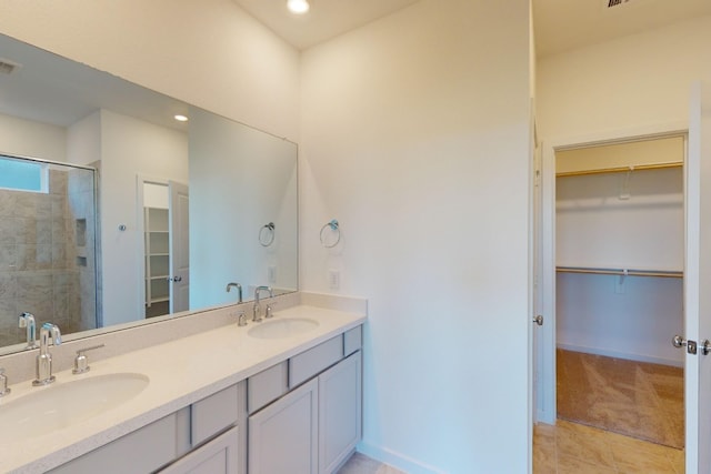 bathroom with double vanity, a sink, a shower stall, and a spacious closet