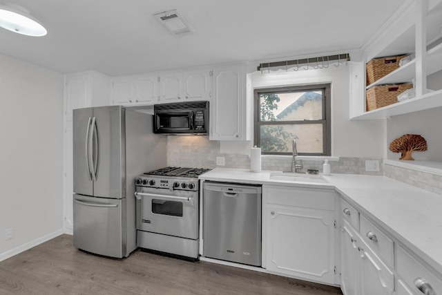 kitchen with visible vents, white cabinets, decorative backsplash, stainless steel appliances, and a sink