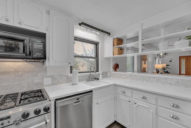 kitchen with stainless steel appliances, a sink, white cabinets, open shelves, and tasteful backsplash