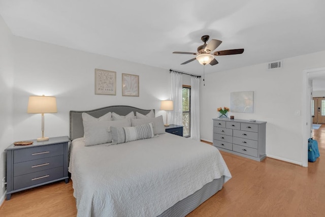 bedroom with a ceiling fan, wood finished floors, visible vents, and baseboards