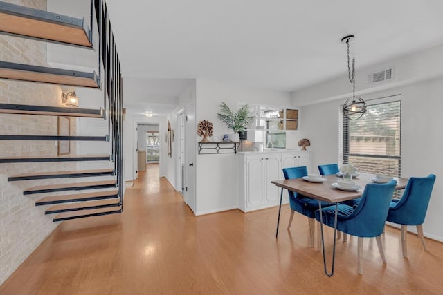 dining area with light wood finished floors, visible vents, and baseboards