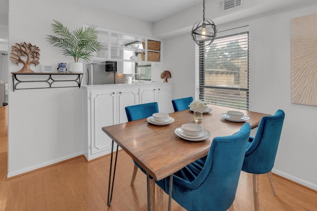 dining space with light wood-style floors, visible vents, and baseboards