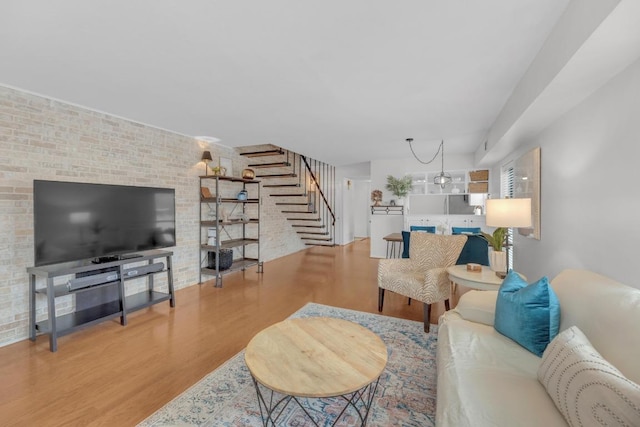 living room with wood finished floors, brick wall, and stairs