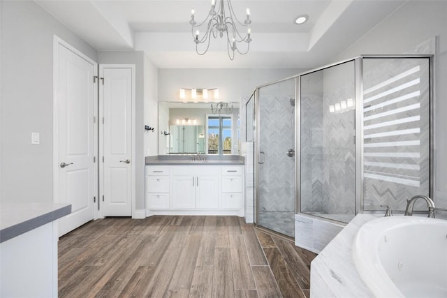 full bathroom featuring a stall shower, wood finished floors, a whirlpool tub, a tray ceiling, and vanity