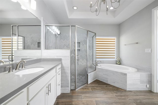 bathroom with a stall shower, wood tiled floor, a tray ceiling, vanity, and a bath