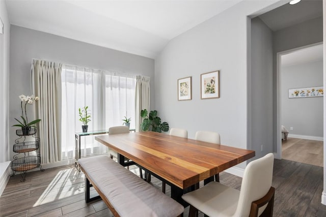 dining area featuring dark wood-style floors, vaulted ceiling, and baseboards