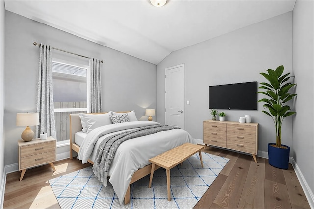 bedroom with lofted ceiling, baseboards, and wood finished floors