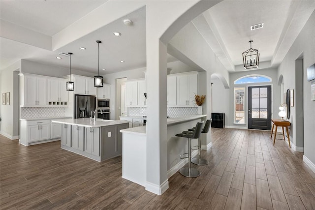 kitchen featuring light countertops, appliances with stainless steel finishes, dark wood finished floors, and a kitchen island with sink