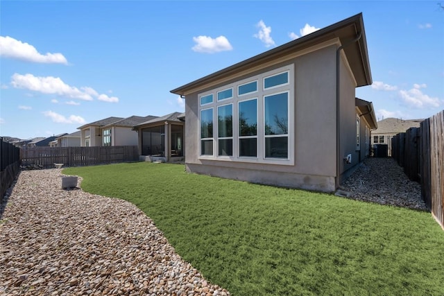 back of property featuring stucco siding, a fenced backyard, and a yard