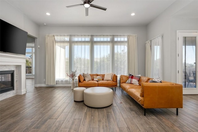 living area featuring recessed lighting, ceiling fan, a tiled fireplace, and wood finished floors