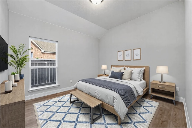 bedroom featuring lofted ceiling, baseboards, and wood finished floors