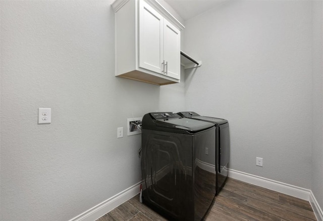 clothes washing area featuring dark wood finished floors, washing machine and clothes dryer, cabinet space, and baseboards