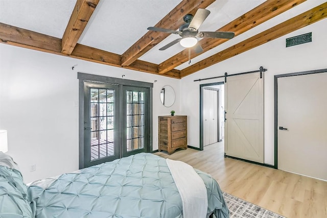 bedroom with a barn door, visible vents, lofted ceiling with beams, light wood-style flooring, and french doors