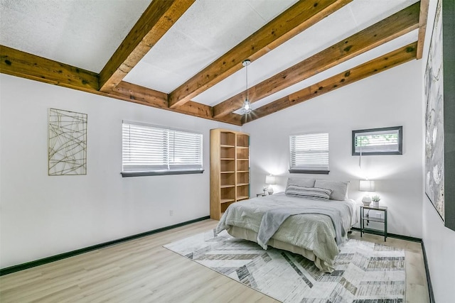 bedroom with lofted ceiling with beams, baseboards, and wood finished floors