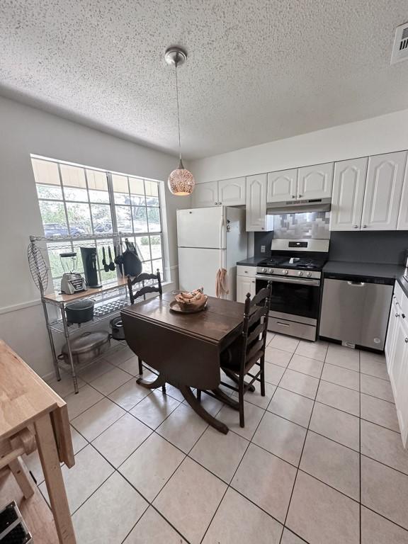 dining room featuring light tile patterned floors, visible vents, and a textured ceiling