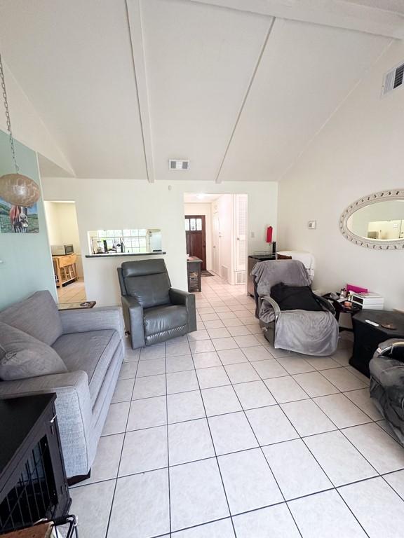 living room with lofted ceiling with beams, light tile patterned floors, and visible vents