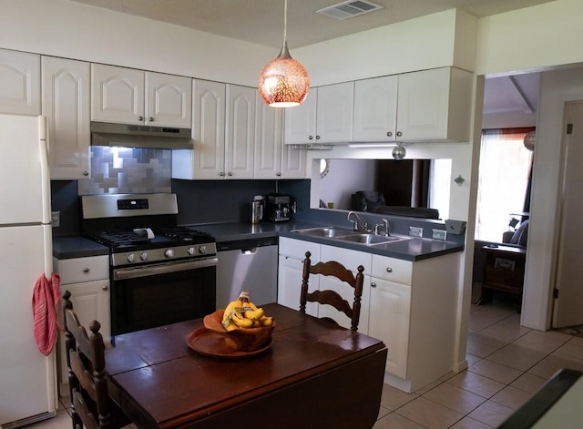 kitchen with stainless steel appliances, dark countertops, a sink, and under cabinet range hood