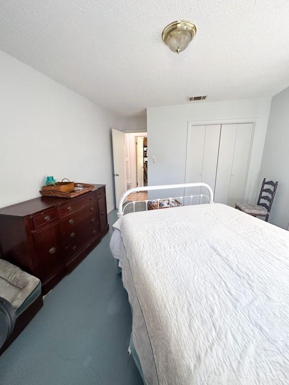 bedroom with visible vents, a closet, carpet flooring, and a textured ceiling