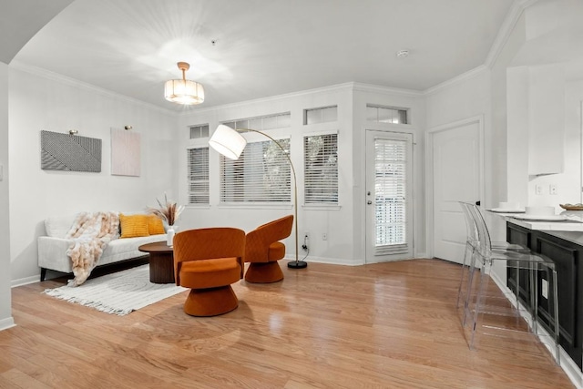 sitting room with light wood-style flooring, ornamental molding, arched walkways, and baseboards