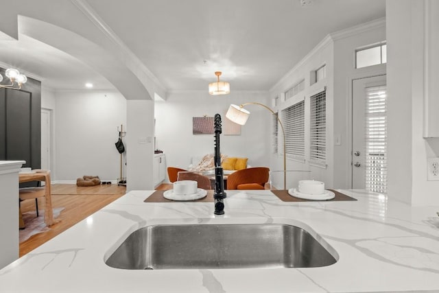 interior details featuring crown molding, arched walkways, pendant lighting, and a sink