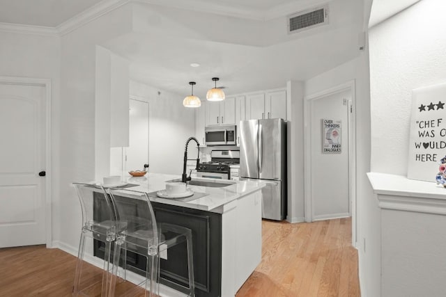 kitchen featuring visible vents, stainless steel appliances, crown molding, light wood-type flooring, and a sink