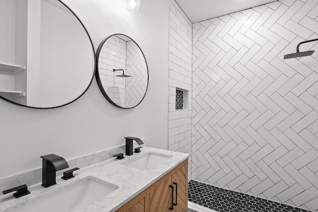 bathroom featuring a sink, a tile shower, and double vanity